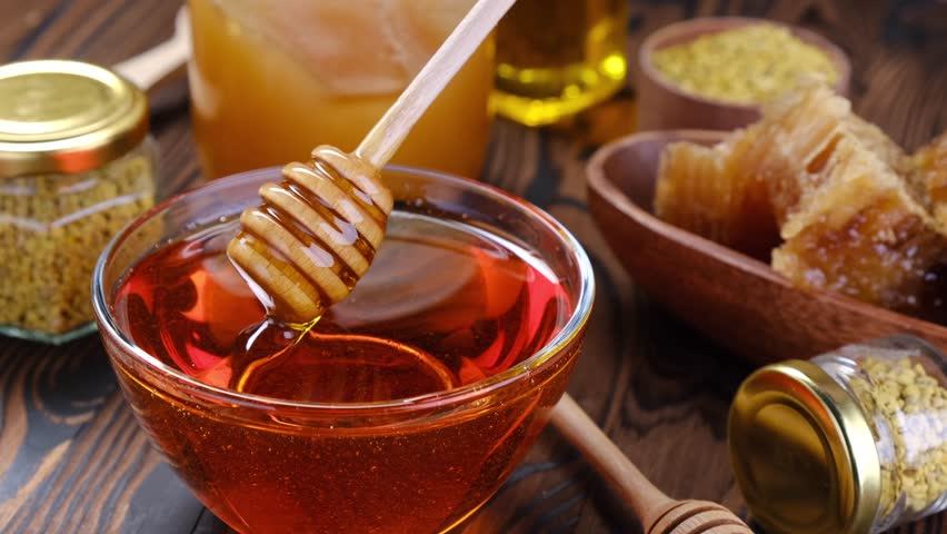 Honey stick and bowl of honey, close-up