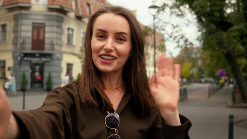 Webcam view selfie holding mobile phone record video recording blog vlog influence smiling talking video call conference talk chat Caucasian woman girl female lady walking in city outdoor go outdoors