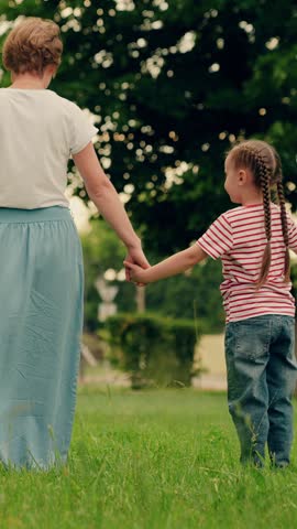 Happy family, child daughter mom play run in park on green lawn. Mother child girl play together holding hands in summer park. Family vacation weekend. Family walks in outdoor in summer. Mom kid girl