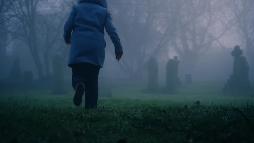 Fearful woman running in eerie Graveyard in thick fog and mist medium 4k shot selective focus