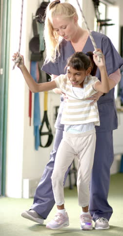 Vertical video: Supporting child with disability, therapist helping during rehabilitation session. therapy, healthcare, medical, physiotherapy, assistance, treatment, slow motion