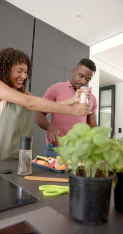 Vertical video: Seasoning vegetables, couple preparing meal together in modern kitchen. Cooking, food preparation, healthy eating, teamwork, culinary, lifestyle