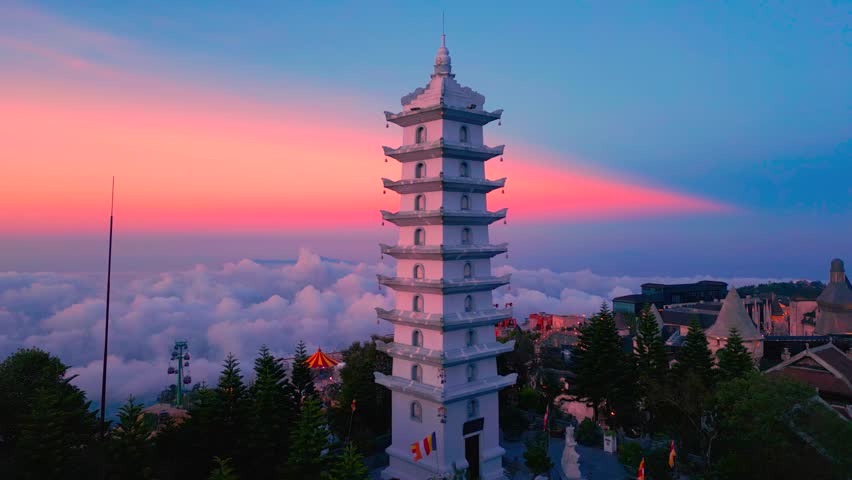 Aerial view of the Ba Na Hills pagoda during sunset, surrounded by clouds and lush greenery in Da Nang, Vietnam.
