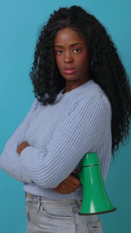 Vertical HD video of serious portrait of black woman holding a megaphone in protest for democracy vote, justice, human rights or racism. Microphone noise and studio speaker isolated on blue background