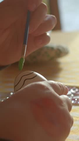 Close-up hand painting Easter egg. Vibrant hues, details of creativity and joy of Easter traditional craft. Festive spirit and crafting springtime decorations Easter eggs close-up. Vertical shot