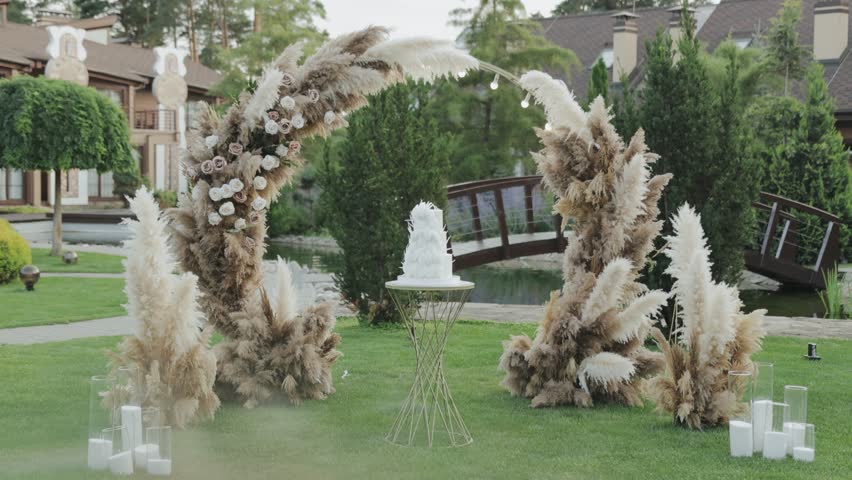 A wedding scene with an elegant cake and a pampas grass arch