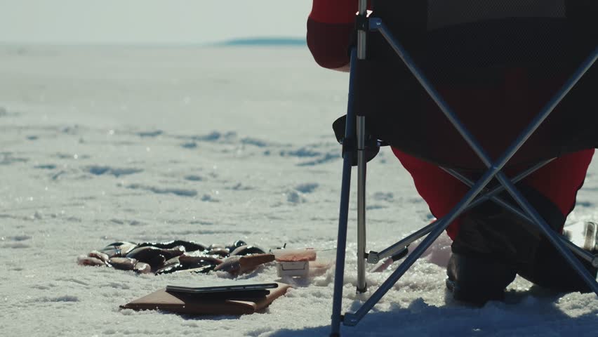 A person enjoys ice fishing in a scenic snowy landscape, fully immersed in the thrill of winter outdoors