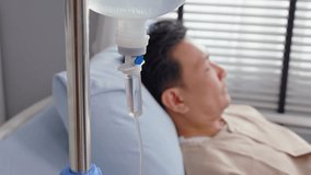 Close up of mature male patient getting saline solution in hospital ward. Senior elderly sick man lying down on bed in the recovery room waiting for treatment from medical doctor in health care clinic - Powered by Shutterstock - Get 15% off with code: PIKWIZARD15