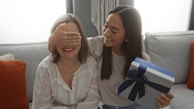 Woman receiving gift box from younger woman in a cozy home living room evoking a loving family bonding moment and joyful togetherness. - Powered by Shutterstock - Get 15% off with code: PIKWIZARD15