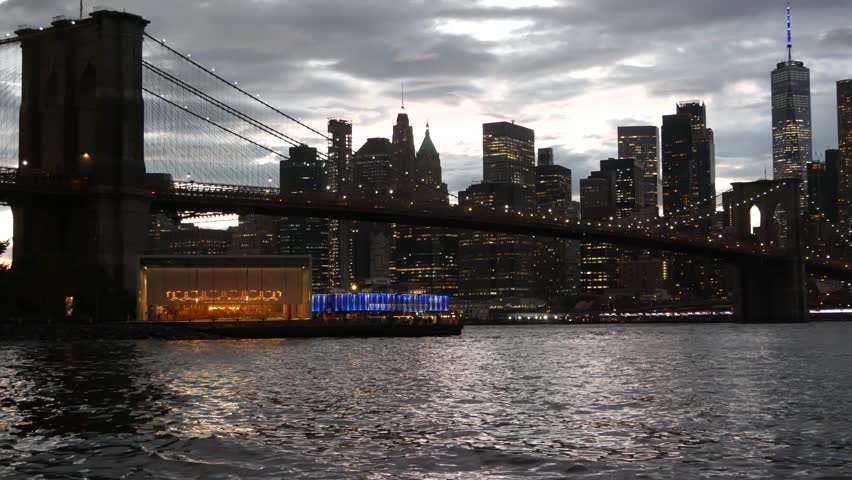 Brooklyn Bridge, New York City Manhattan downtown skyline cityscape, United States. Waterfront Pebble Beach, carousel in Dumbo, USA. Dramatic twilight dusk. Evening or night sky. World Trade Center.