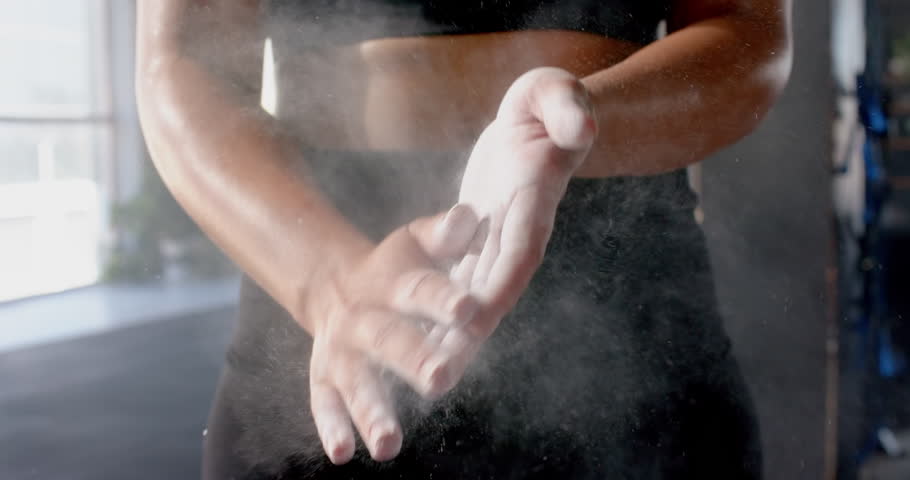 Clapping hands with chalk dust, woman preparing for workout in gym. Fitness, preparation, exercise, training, strength, motivation