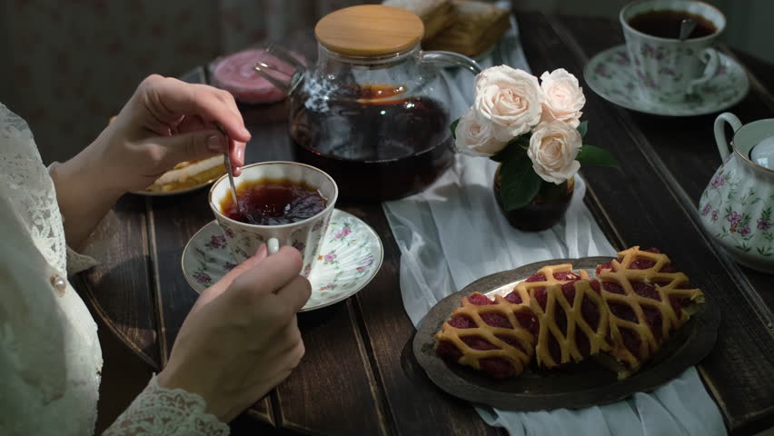 Tea time. Woman having morning breakfast with cup of tea and fresh pastries in cozy kitchen.