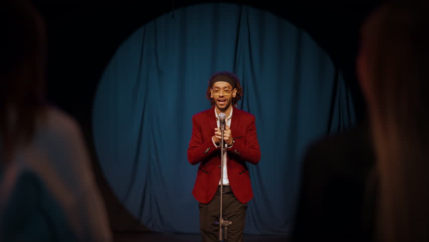 Trendy event and performance on stage, african american man with microphone. Portrait of handsome charismatic male person speaking to microphone, stand-up comedy show and presentation, entertainment