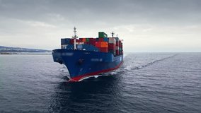 Front view of a blue container ship sailing through calm waters under a cloudy sky, heading towards the port - Powered by Shutterstock - Get 15% off with code: PIKWIZARD15
