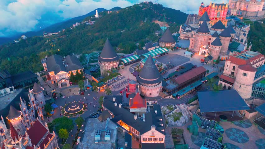 Aerial view is lunar castles of Bana Hills at pink sunset time with clouds down. The famous tourist destination of Da Nang, Vietnam. Near Golden bridge.