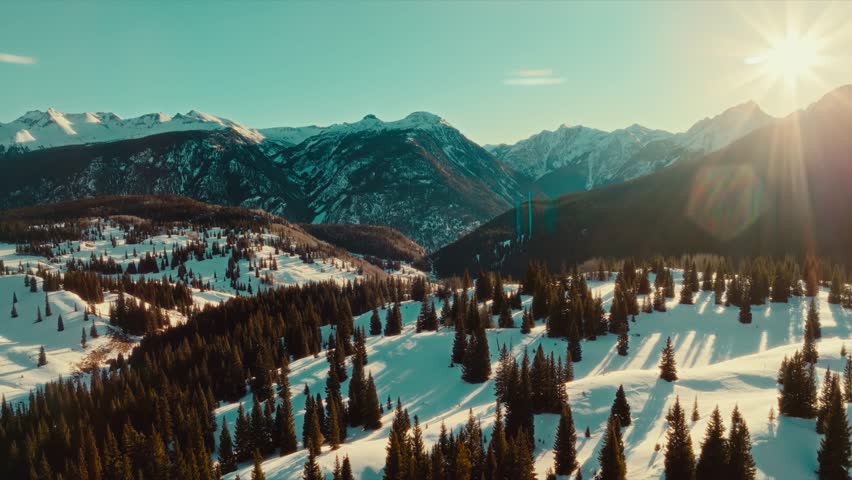 4K aerial drone over snow capped mountain peaks, Rocky Mountains, Colorado. Evergreen trees contrast against snow. Jagged ridges dusted with snow. Majestic. The essence of Colorado’s winter beauty.