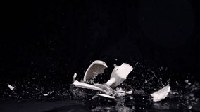 A bright mug falls and shatters on the floor in slow motion, with fragments scattering in all directions against a matte black background. - Powered by Shutterstock - Get 15% off with code: PIKWIZARD15