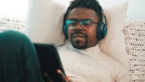 graphics designer freelancer working in home, portrait of African American man using tablet and stylus for sketching, listening to music by wireless headphones in living room, remote work - Powered by Shutterstock - Get 15% off with code: PIKWIZARD15