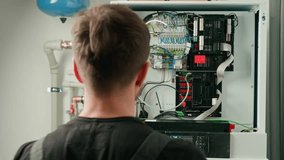Technician working on internal wiring of heat pump, inspecting electrical connections. Specialist servicing heating and cooling system. Electrician with screwdriver tightening screws on control panel - Powered by Shutterstock - Get 15% off with code: PIKWIZARD15
