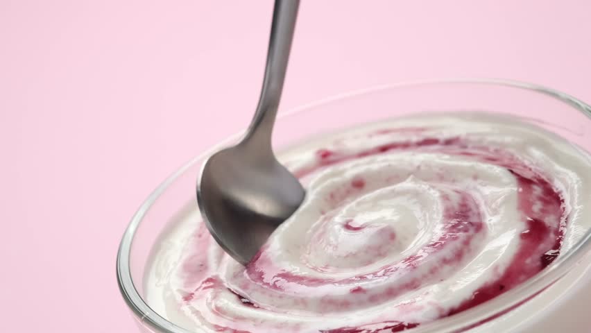 Close-up spoon scooping berry yogurt from package, fresh and creamy dessert