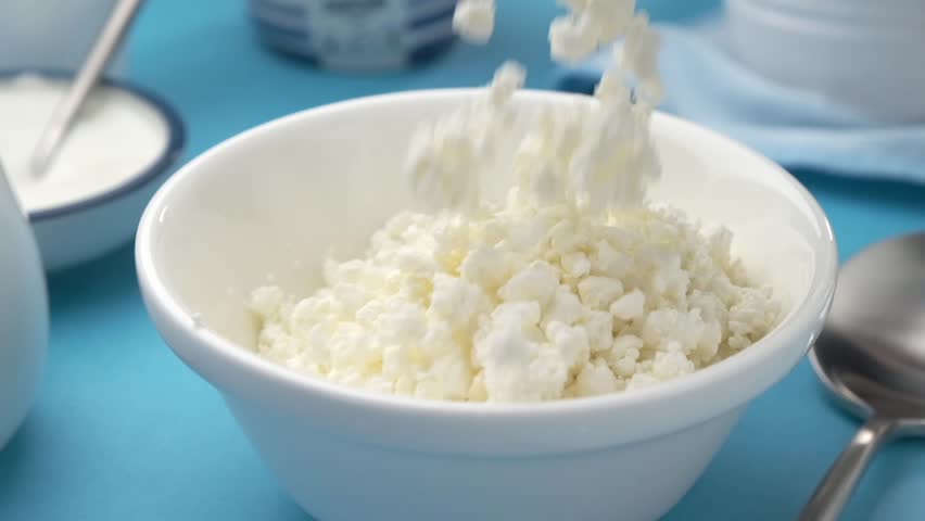 Falling cottage cheese close-up, dairy products in the background