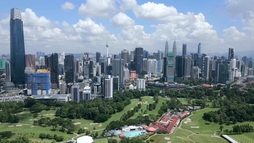 Aerial view of Kuala Lumpur city skyline and golf courses on sunny day, Malaysia.