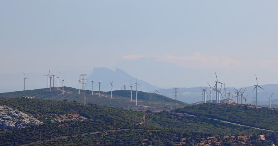 Wind turbines on a hillside, clean energy against a mountain backdrop. The Rock of Gibraltar on background.