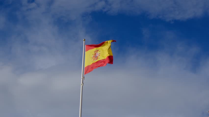 Spanish flag waving gracefully against a bright blue sky. A powerful symbol of national pride, unity, and heritage, capturing the essence of Spains cultural identity