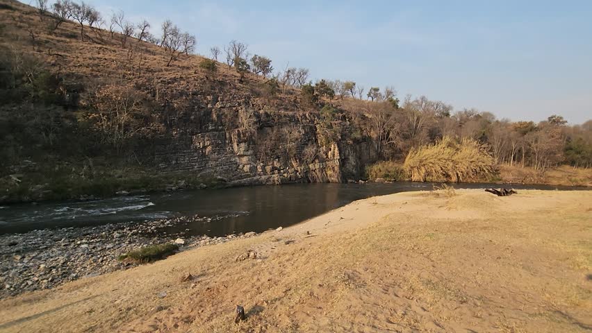 Rocky cliffs overhang a tranquil river in South Africa