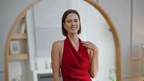 Glamorous woman in red dress posing in large mirror admiring elegant outfit closeup. Stylish lady moving gracefully enjoying reflection. Chic brunette showcasing fashion clothing at home apartment. - Powered by Shutterstock - Get 15% off with code: PIKWIZARD15