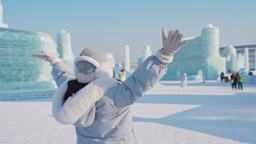 Young happy female tourist enjoying at ice and snow world festival in Harbin, China