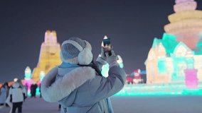 Young happy female tourist enjoying and taking photo in ice and snow world festival at night in Harbin, China - Powered by Shutterstock - Get 15% off with code: PIKWIZARD15
