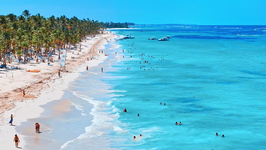 Best beaches in the world. Top view of a hotel beach of tropical islands on the shores of the blue sea. Dominican Republic, Punta Cana. White sand, beautiful beach, tall palms. Relax on blue sea water