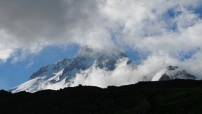 Timelapse of Kazbegi mountain in Caucasus mountain ridge. Snow-capped peaks with clouds moving around, time passing fast. Stunning nature scenery suitable for travel, adventure, nature lovers. - Powered by Shutterstock - Get 15% off with code: PIKWIZARD15