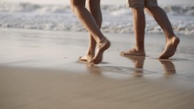 People's feet walk barefoot in sea surf waves. Couple leave footprints on wet sand. Two person's legs go along ocean shore. Man, woman stroll on sandy beach. Low angle shot with reflections. - Powered by Shutterstock - Get 15% off with code: PIKWIZARD15
