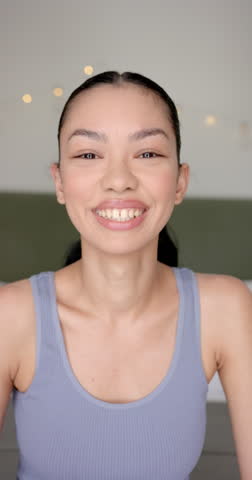 Vertical video: Smiling woman in casual tank top looking at camera, feeling happy and relaxed. Happiness, portrait, lifestyle, positive, emotions, slow motion