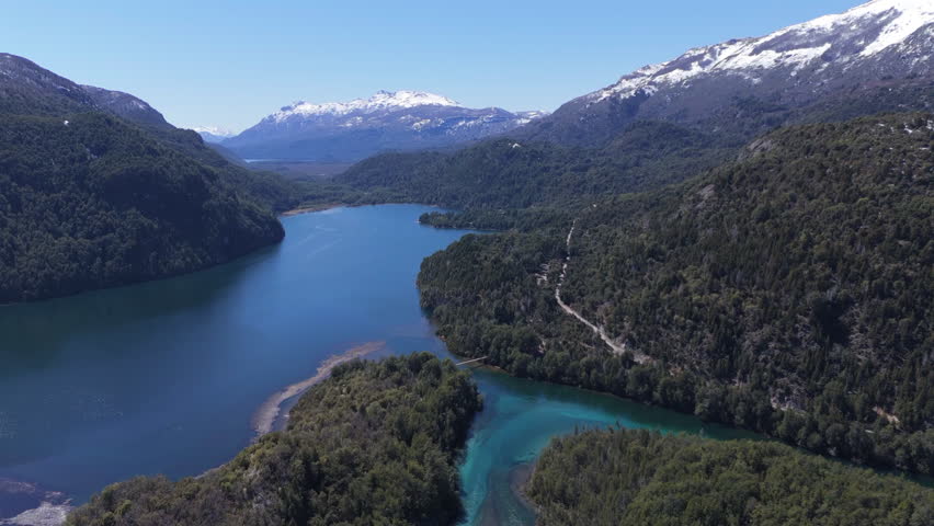 Downward aerial movement of a serene mountain lake surrounded by forest at Parque Nacional Los Alerces, Patagonia, Argentina.