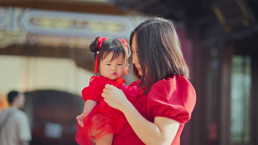Happy asian mother wearing Chinese dress with baby in Chinese Temple, Chinese New Year