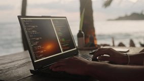 Web developer types on laptop at beach cafe with sunset over ocean. Male software coder creates code for project amid palms, sea. Remote work concept combines leisure, pro tasks. Slow motion. - Powered by Shutterstock - Get 15% off with code: PIKWIZARD15
