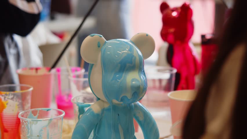 During master class on making children's toys in the shape of bear, head of figurine is coated with epoxy paint, creating unique works of art and sculpture.
