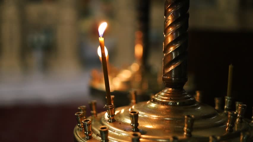 A small church candle burns on a candlestick in the church. Orthodox Church Candle Stand with Candles.
