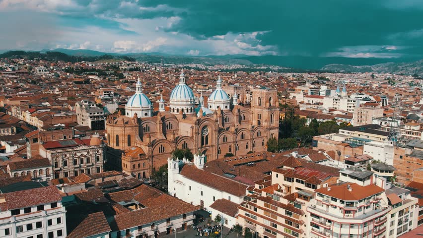 Aerial view of Cuenca, Ecuador: colonial architecture, cobblestone streets, iconic blue domes, and lush mountains. Perfect for travel, culture, and cityscape footage