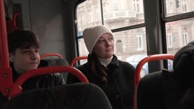 A woman in a white hat and a teenage boy with headphones sit on a tram, gazing out the window at a city scene. Ideal for public transport, urban life, and everyday moments. - Powered by Shutterstock - Get 15% off with code: PIKWIZARD15