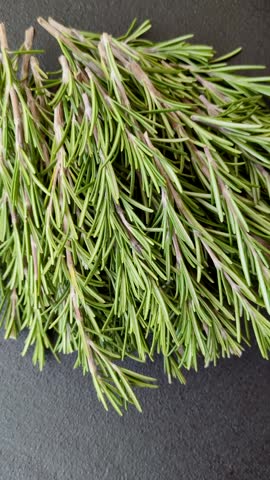 Fresh green rosemary sprigs prepared for cooking, on dark concrete background