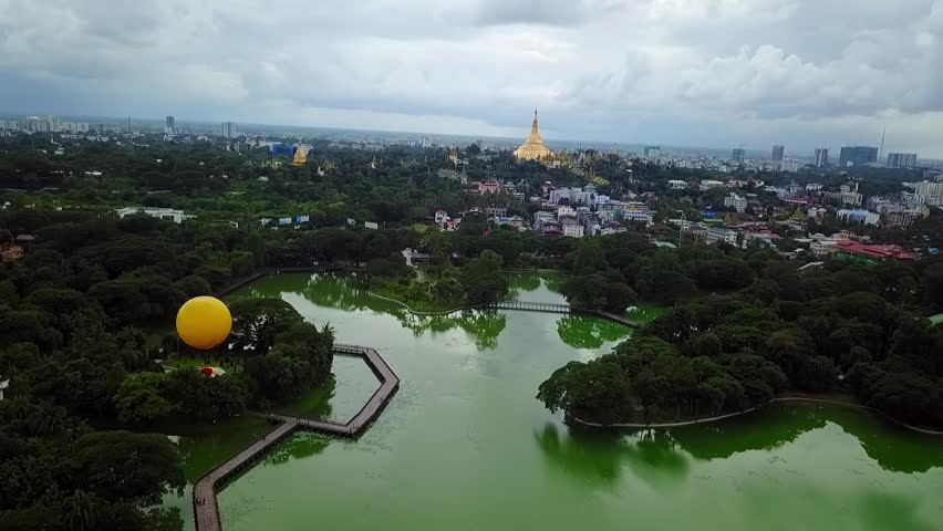 A sweeping panoramic aerial shot of Yangon, Myanmar, featuring the tranquil Kandawgyi Lake and the majestic Shwedagon Pagoda, providing a stunning view of the city and its cultural landmarks.