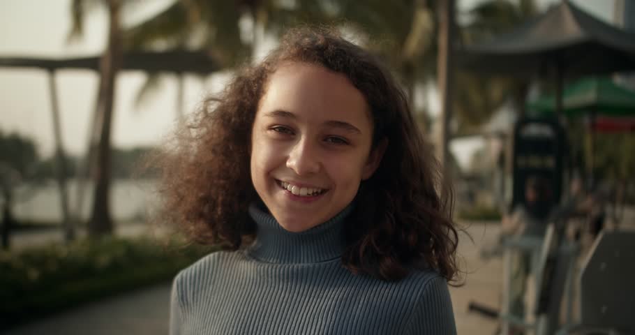 Beautiful happy cute child face adorable girl, close up portrait child. Happy girl in rays of the sun. Girl face in park. Beautiful happy cute child face adorable girl, close up portrait child. 4K