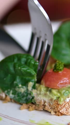 eat with fork and knife avocado toast cut off piece small cherry tomatoes and basil leaf lunch decorations