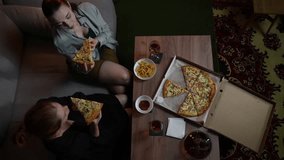 Top view of two female friends taking slices of delicious pizza from the box and smelling them. Slow motion view of women going to eat tasty Italian food sitting at home in the evening. Dinner time - Powered by Shutterstock - Get 15% off with code: PIKWIZARD15