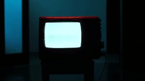 Old analog television set displaying static white noise in dark room - Powered by Shutterstock - Get 15% off with code: PIKWIZARD15