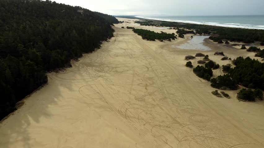 USA, OR, Reedsport, Umpqua Beach, 2024-11-24 - Drone view of the Oregon Dunes at the Umpqua River Lighthouse with ATV tracks in the sand on a rainy day.